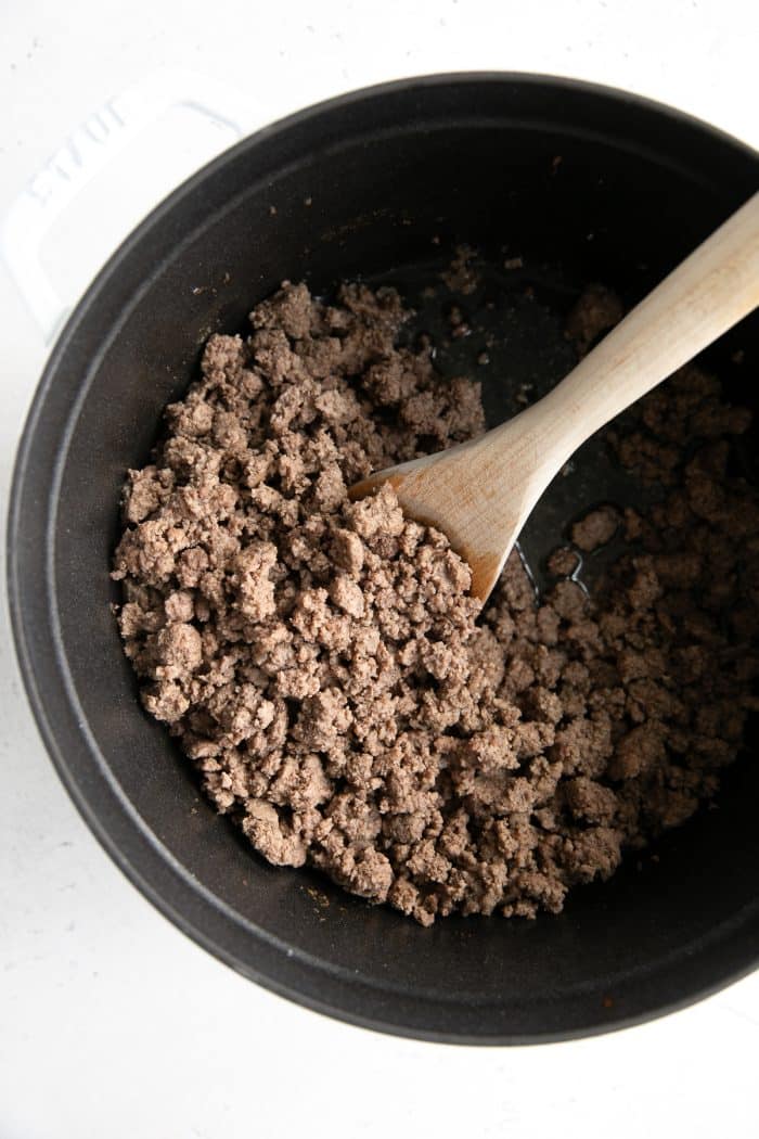 Ground beef cooking in a large white pot.