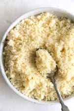 Spoonful and bowl filled with cooked Moroccan couscous.