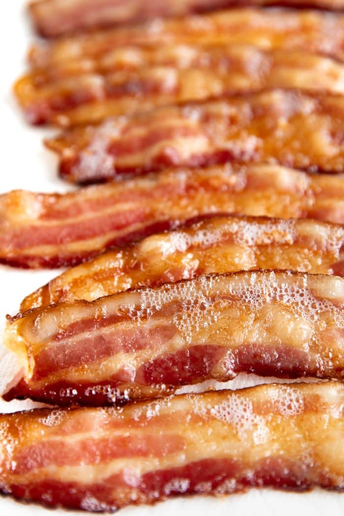 Fully cooked oven cooked bacon on a baking sheet lined with paper towels.