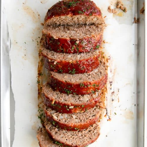 Large cooked meatloaf sliced into large thick slices.