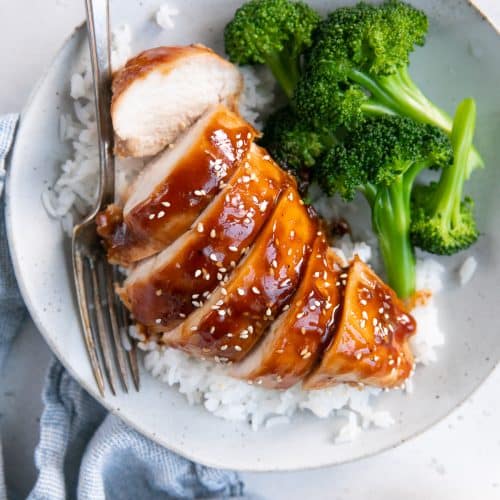 Overhead image of a white plate with cooked basmati rice, baked teriyaki chicken breast, and steamed broccoli.