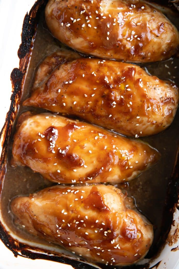 Close up image of baked easy chicken teriyaki recipe in a large white baking dish.