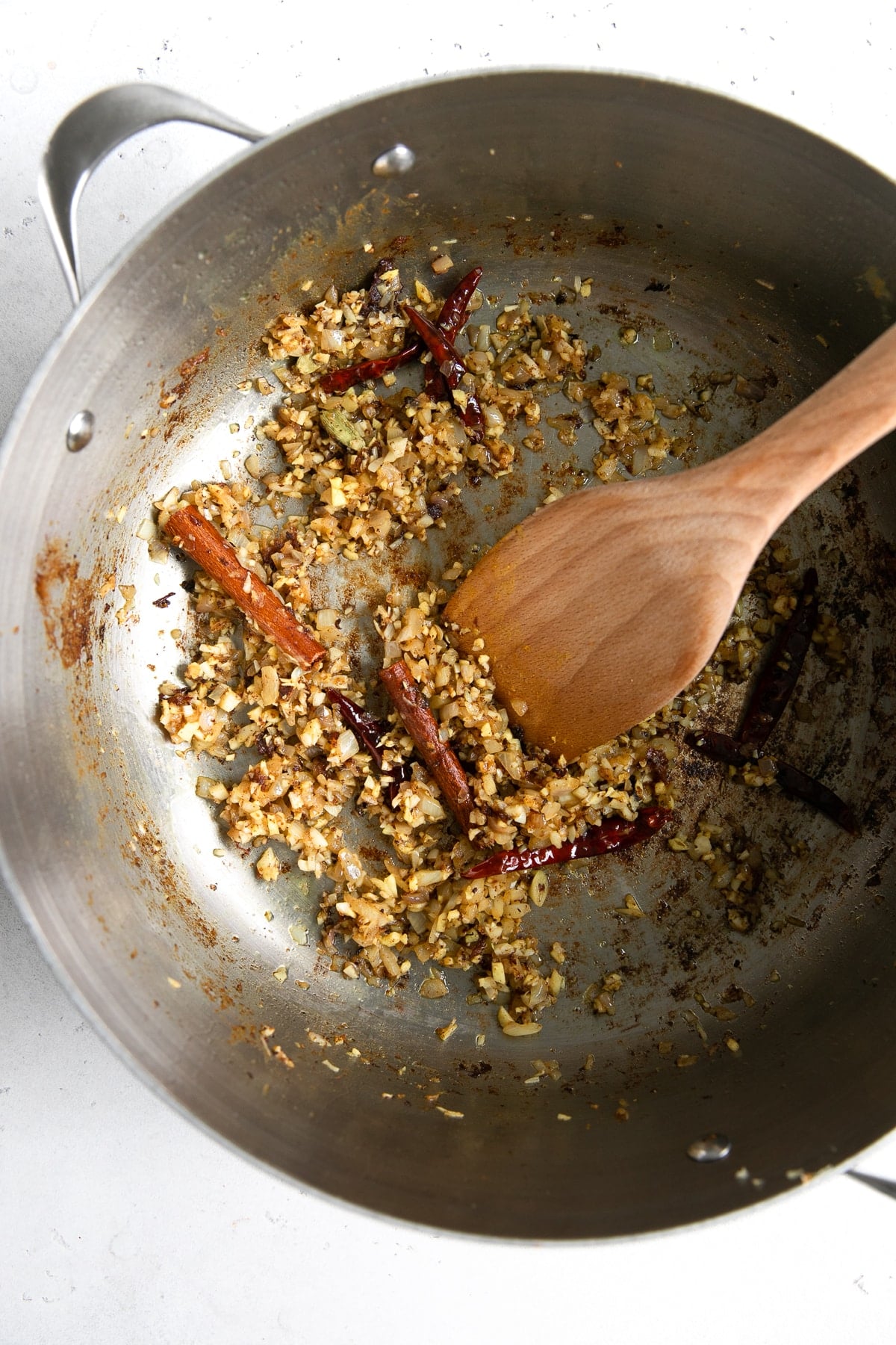 Sautéing aromatics in a large heavy-bottomed skillet.