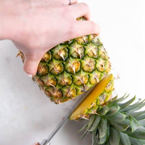Cutting the top off of a pineapple.