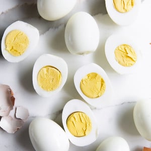 Perfect peeled hard boiled eggs, half have beef sliced in half lengthwise with a creamy yellow yolk.