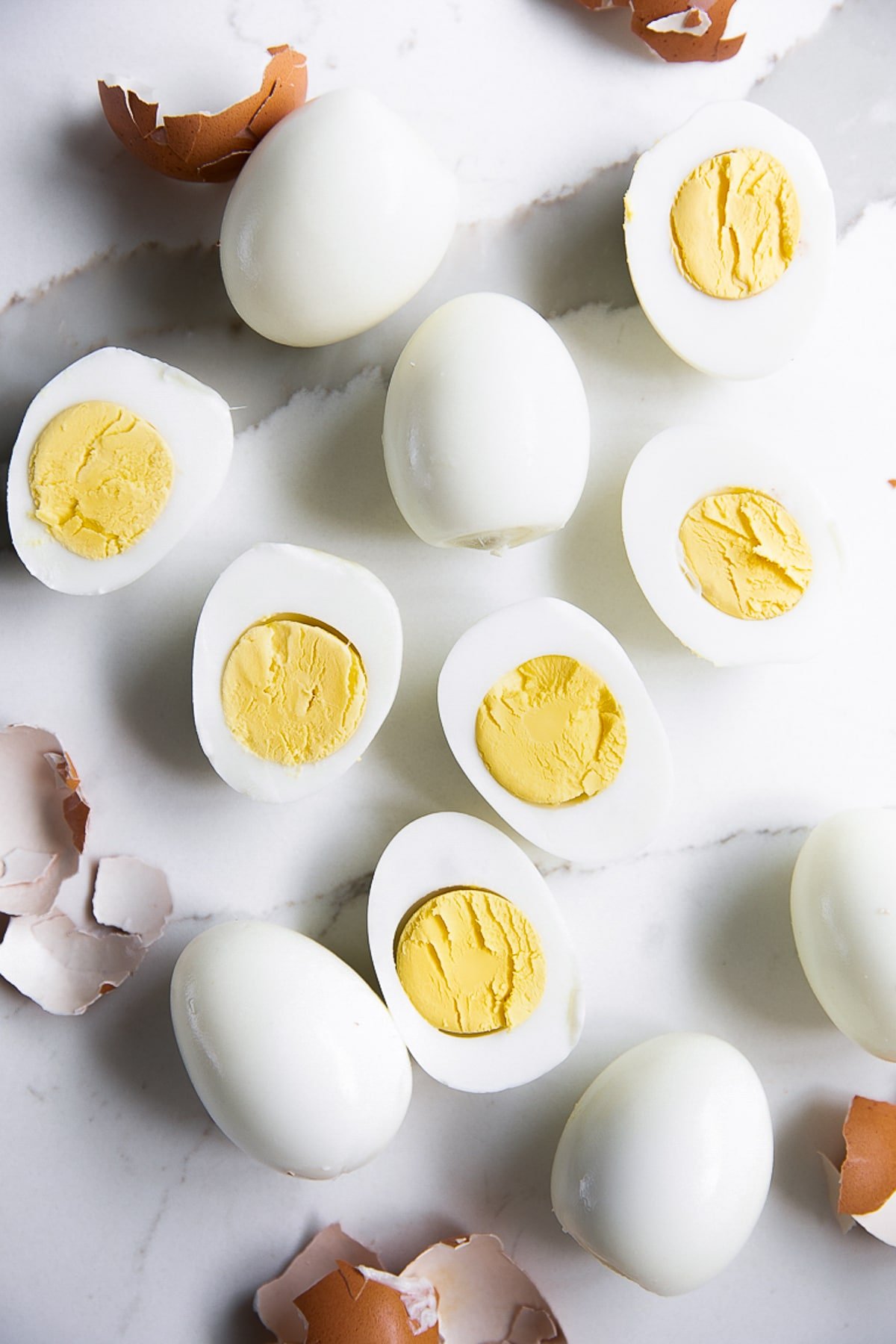 Perfect peeled hard boiled eggs, half have beef sliced in half lengthwise with a creamy yellow yolk.