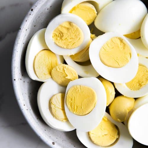 Bowl filled with perfect hard boiled eggs with creamy yellow yolks.