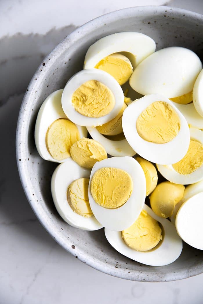 Bowl filled with perfect hard boiled eggs with creamy yellow yolks.
