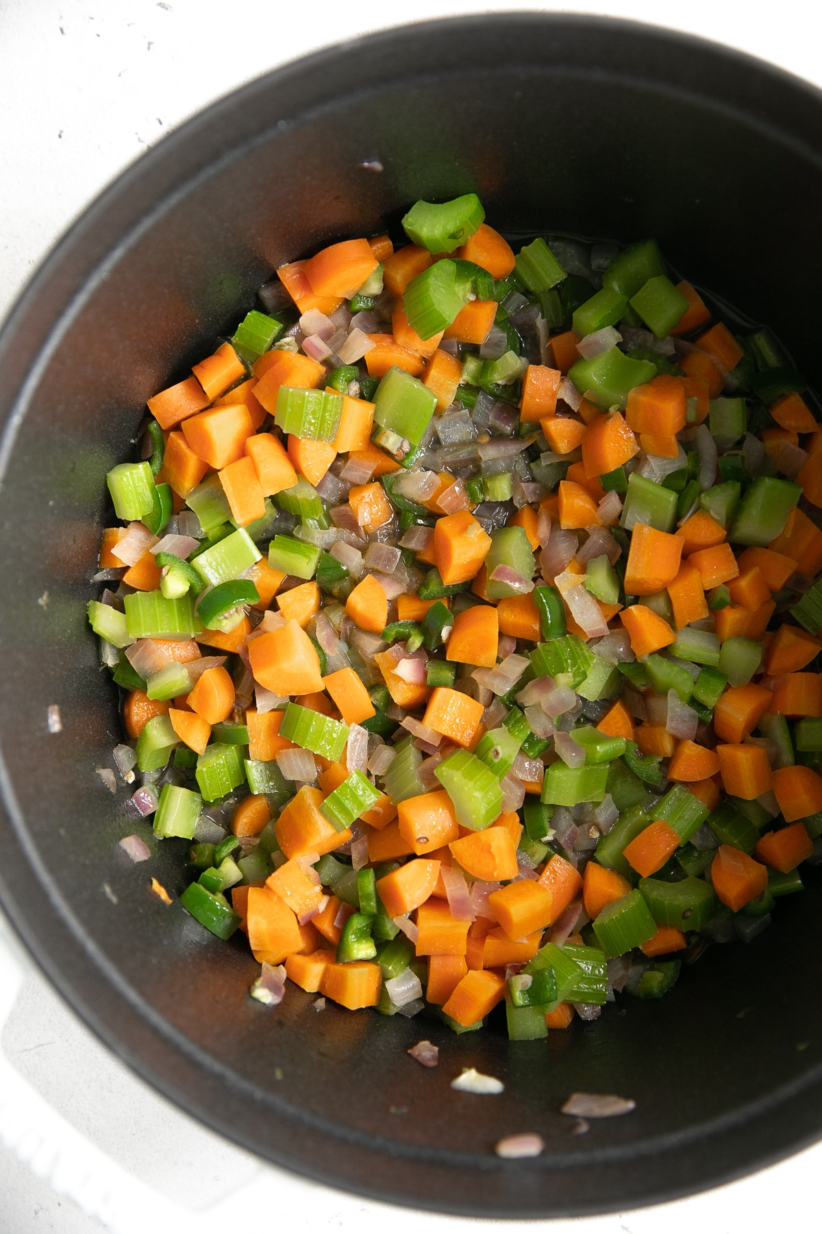 Large pot filled with cooking onions, celery, and carrots.