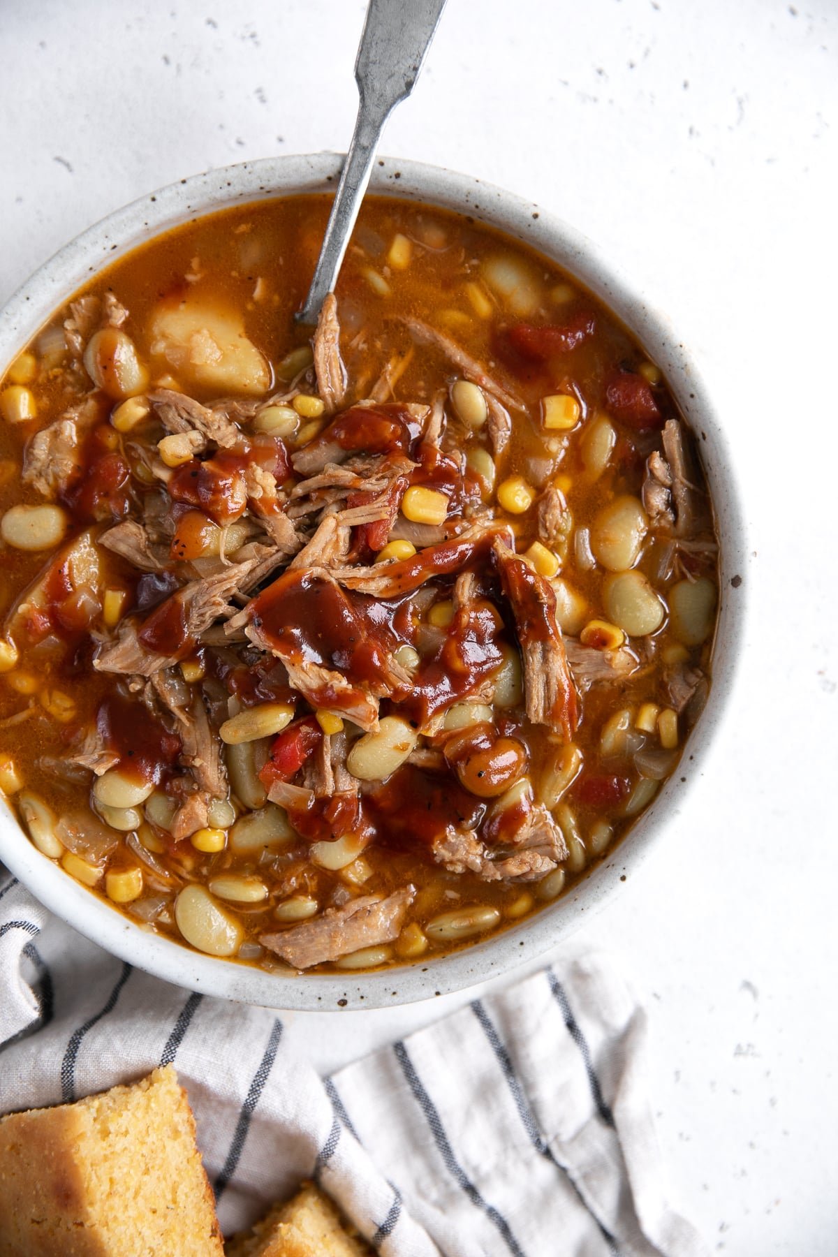 Over head image of a bowl filled with Brunswick stew and served with a side of freshly baked cornbread.