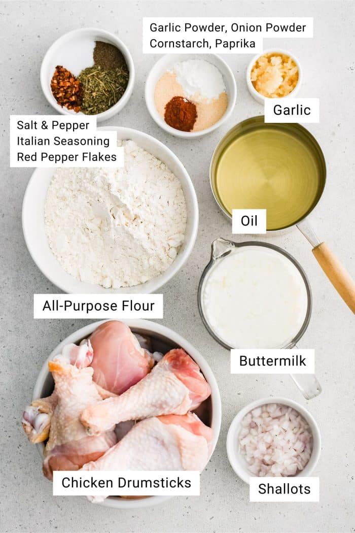 Ingredients for buttermilk fried chicken measured and set aside in individual serving bowls with text overlay.