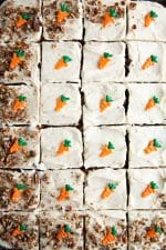 Carrot sheet cake sliced into 24 pieces and topped with individual handmade chocolate carrots and crushed pecans.