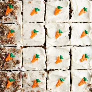 Carrot sheet cake sliced into 24 pieces and topped with individual handmade chocolate carrots and crushed pecans.