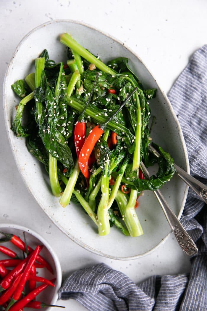 White serving plate filled with sauteed Chinese broccoli in soy sauce and garlic.