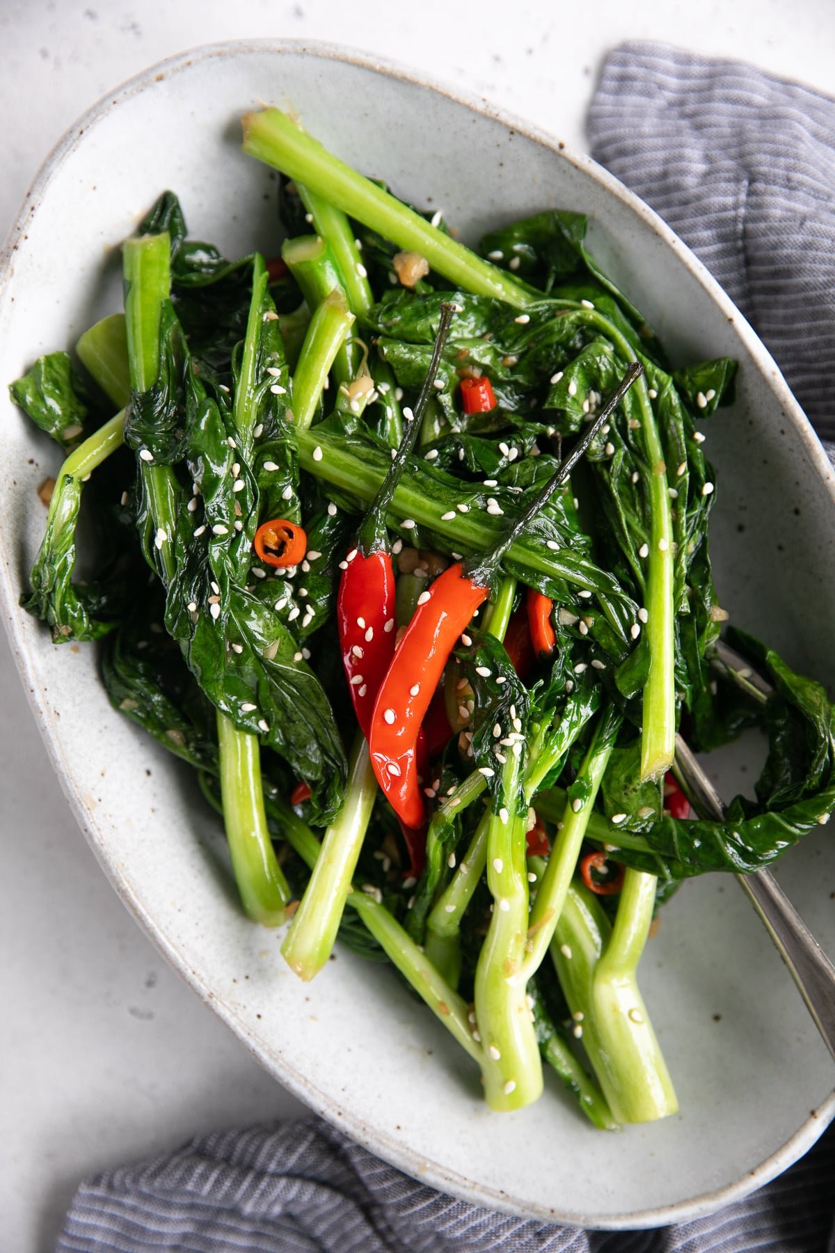 Oval serving plate filled with stir fried Chinese broccoli garnished with sesame seeds.