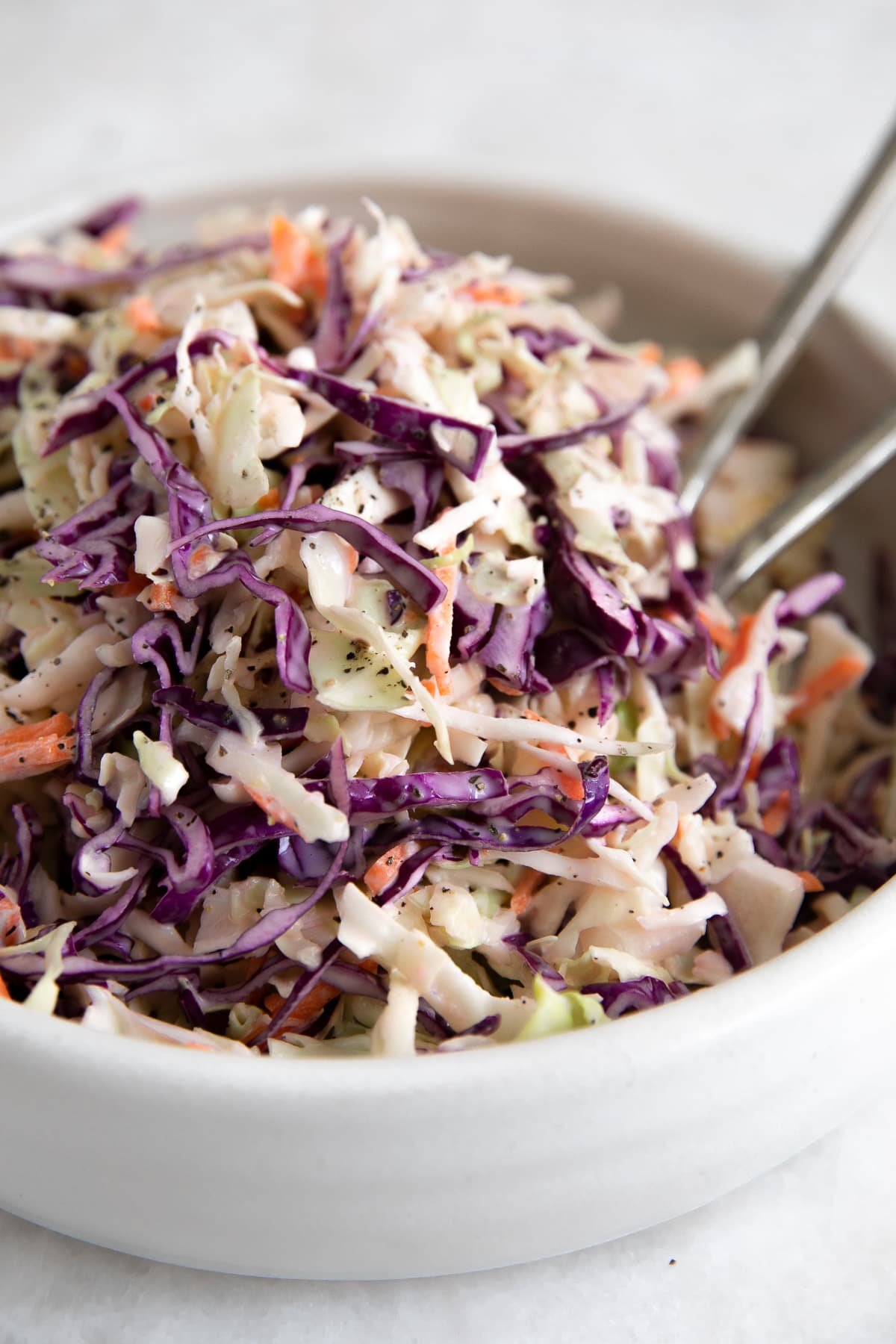Large white shallow serving bowl filled with creamy classic coleslaw.