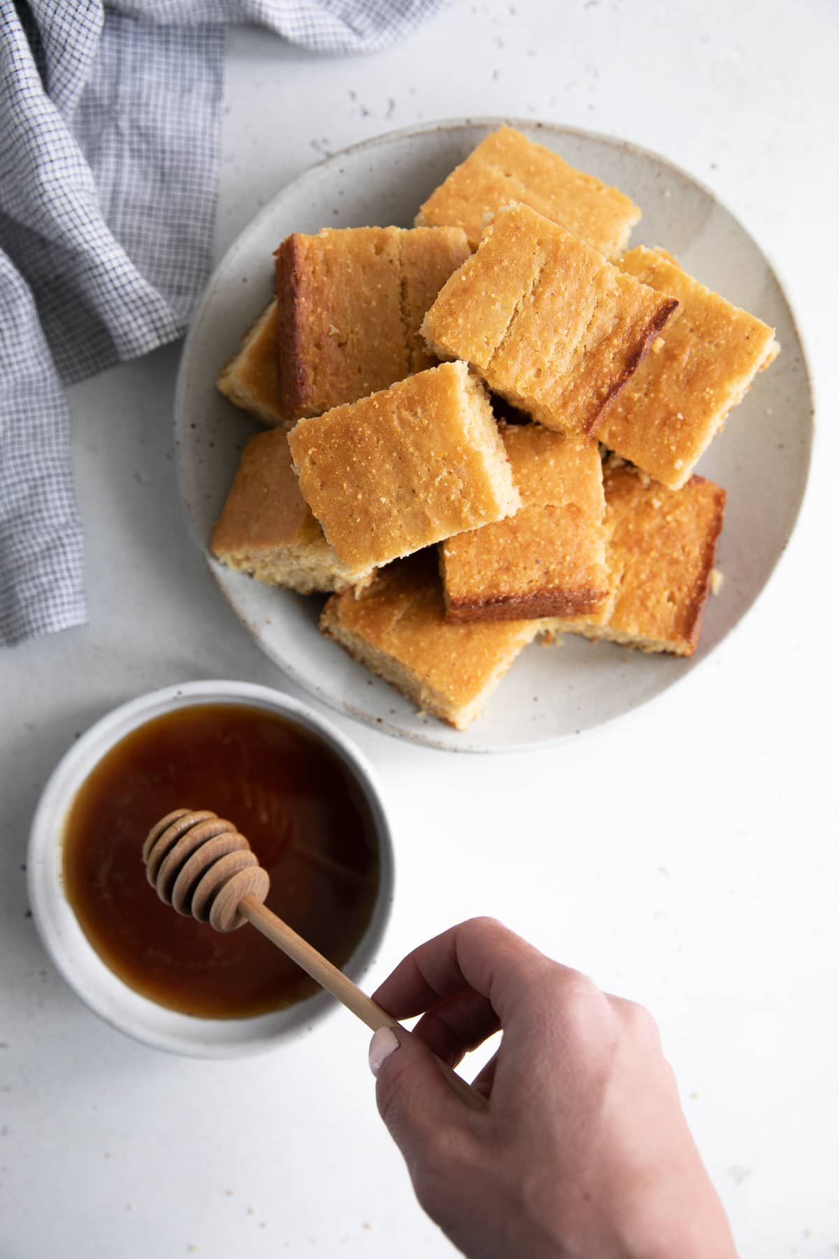 Cornbread on a plate with honey in a small bowl.