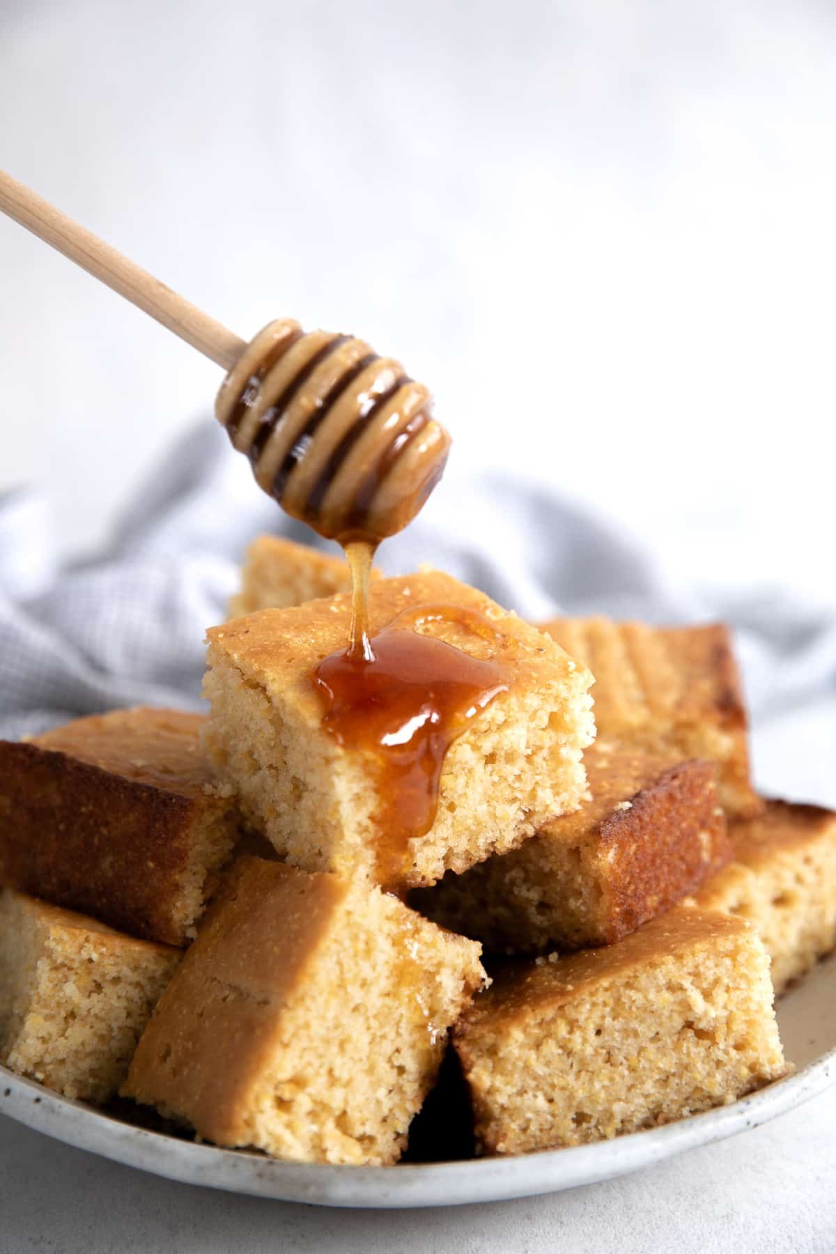 Honey being drizzled over freshly baked cornbread.