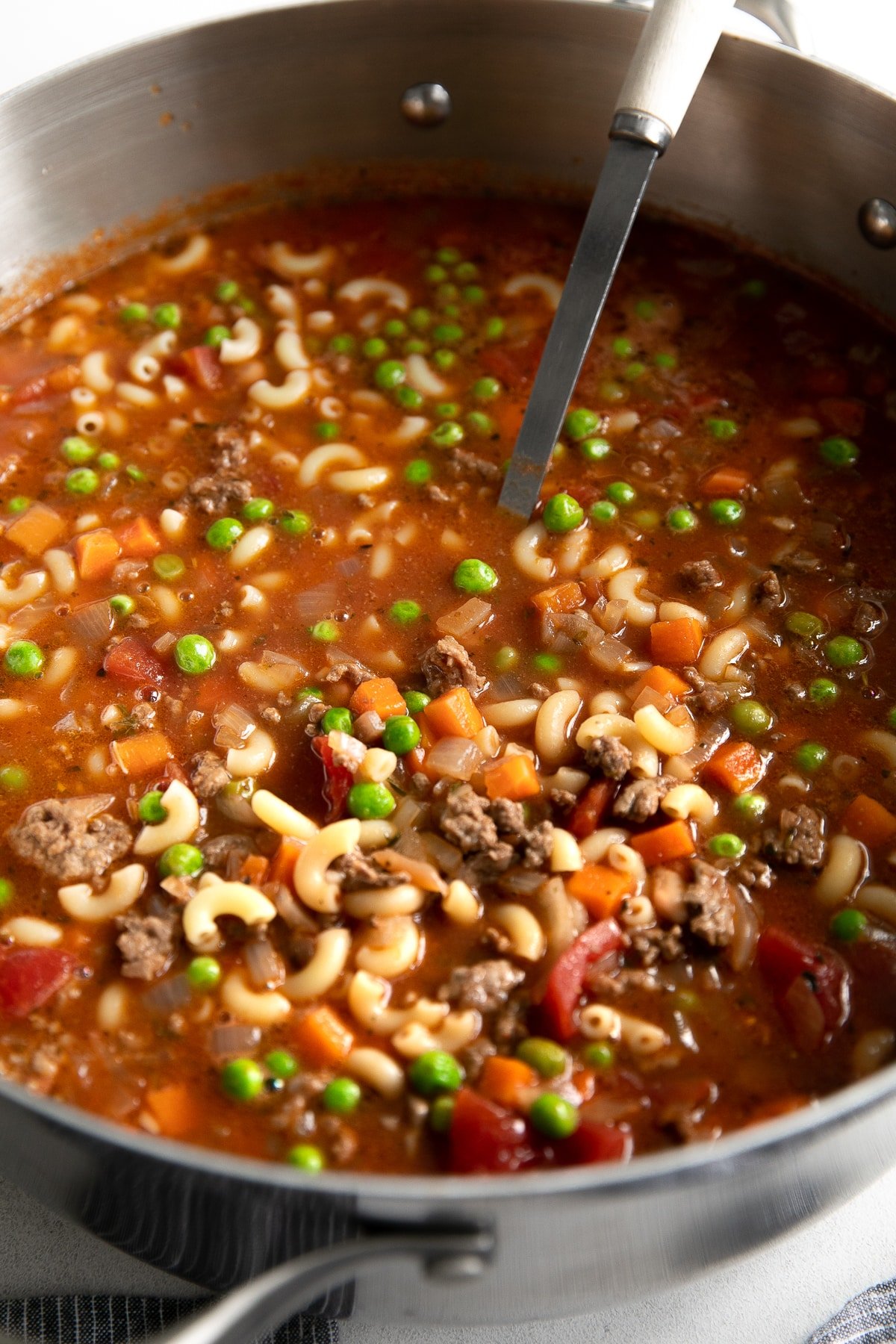 Large pot filled with Hamburger Soup made with ground beef, tomatoes, macaroni noodles, peas, and carrots.