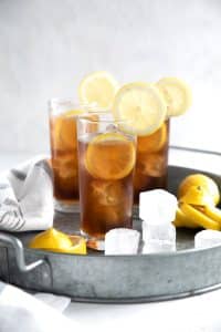 Three ice-cold Long Island Iced Tea on a large metal serving tray.