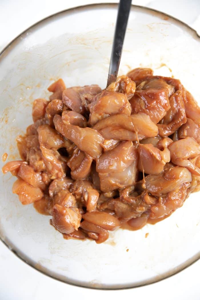 Chicken pieces marinating in a mixture of soy sauce, oil, and cornstarch.