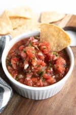 Homemade salsa in a small white bowl served with tortilla chips.