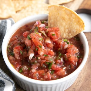 Homemade salsa in a small white bowl served with tortilla chips.