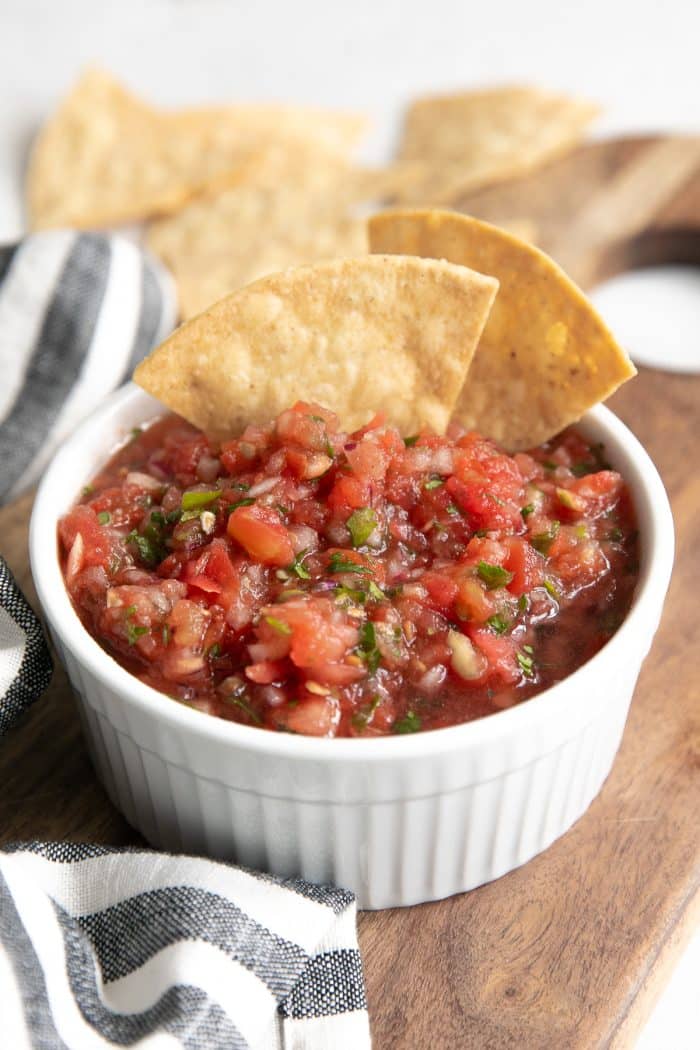 Homemade salsa in a small white bowl served with tortilla chips.