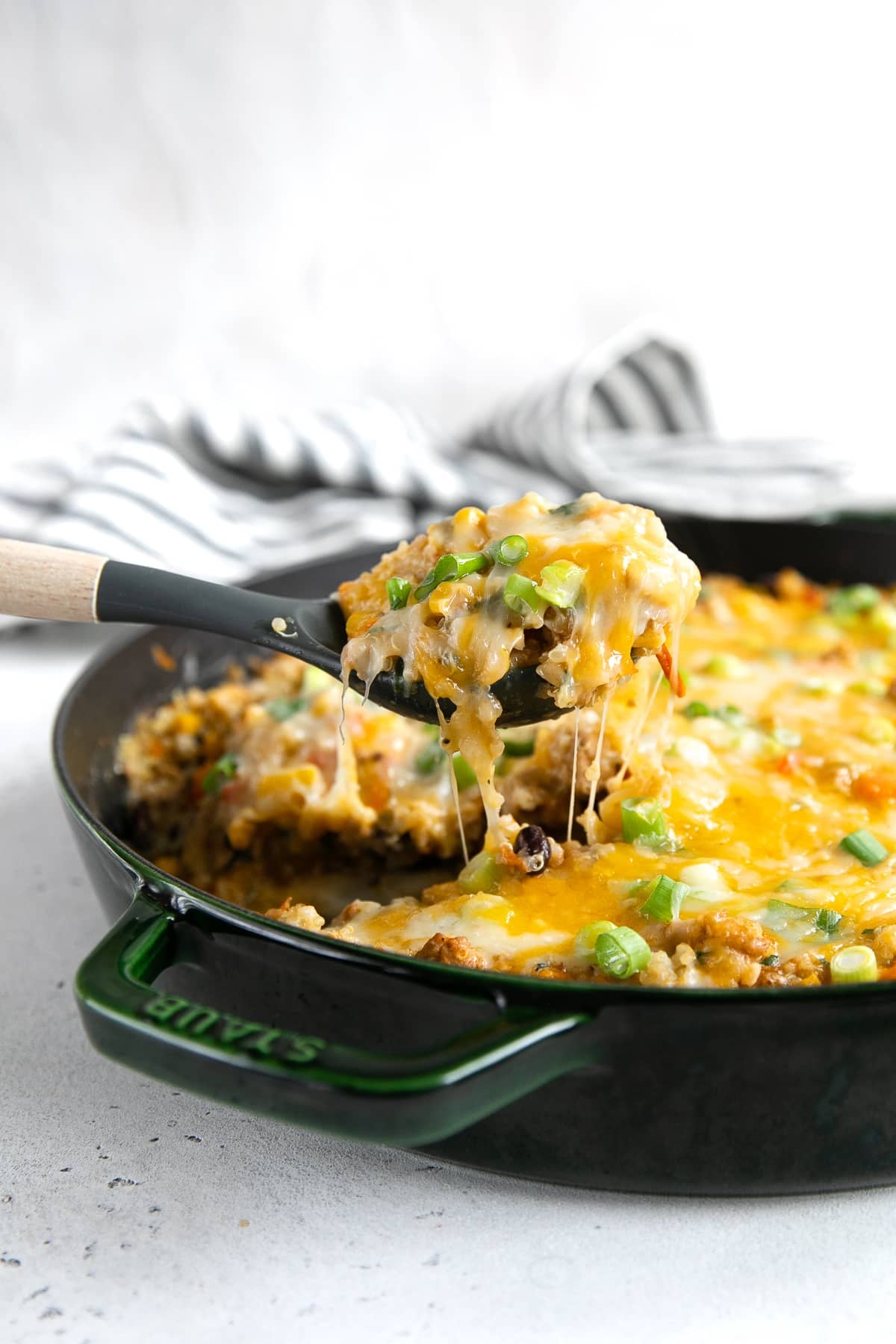 A pan of Quinoa Casserole with melting cheese being lifted