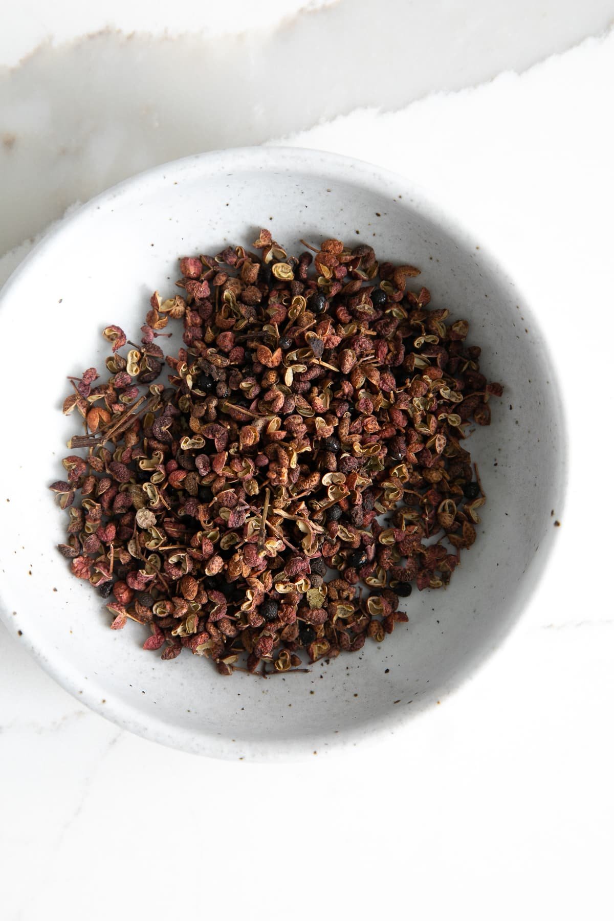 Small bowl filled with szechuan peppercorns.