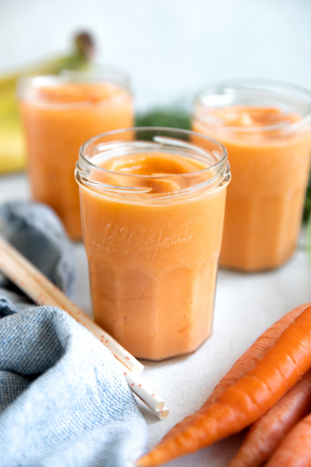 Three glasses filled with icy cold tropical carrot smoothie.