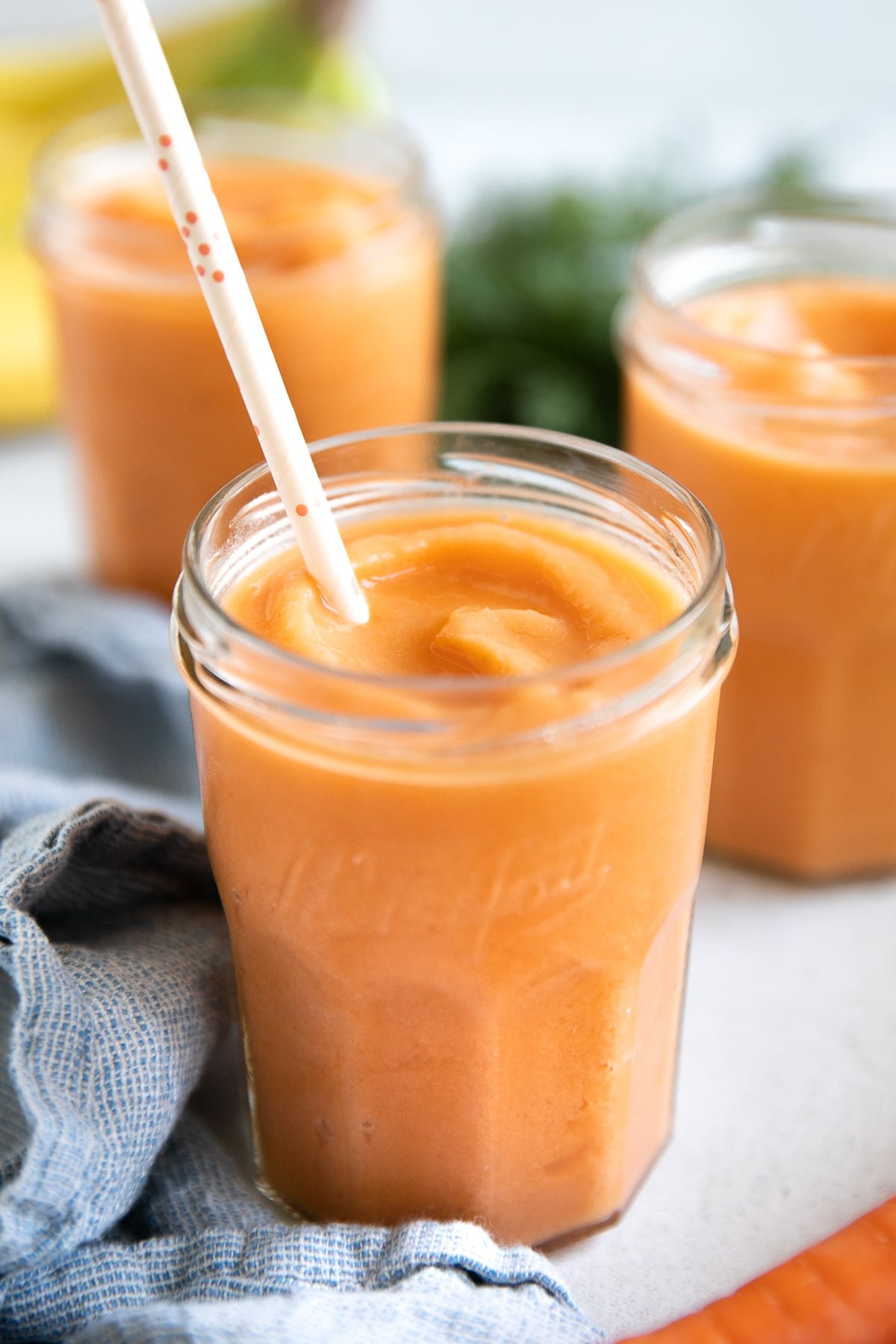 Three glasses filled with icy cold tropical carrot smoothie.