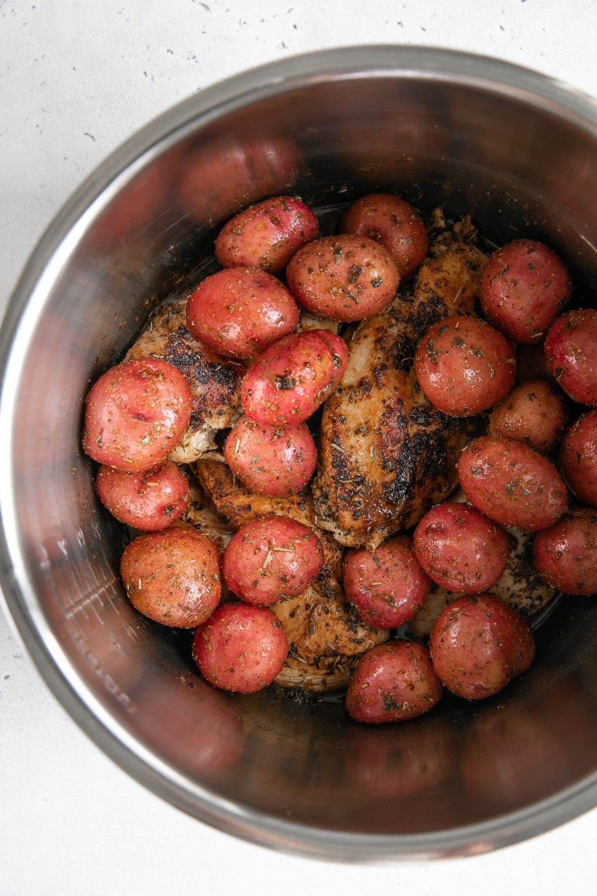 Seared chicken breasts and baby red potatoes in a large Instant Pot.
