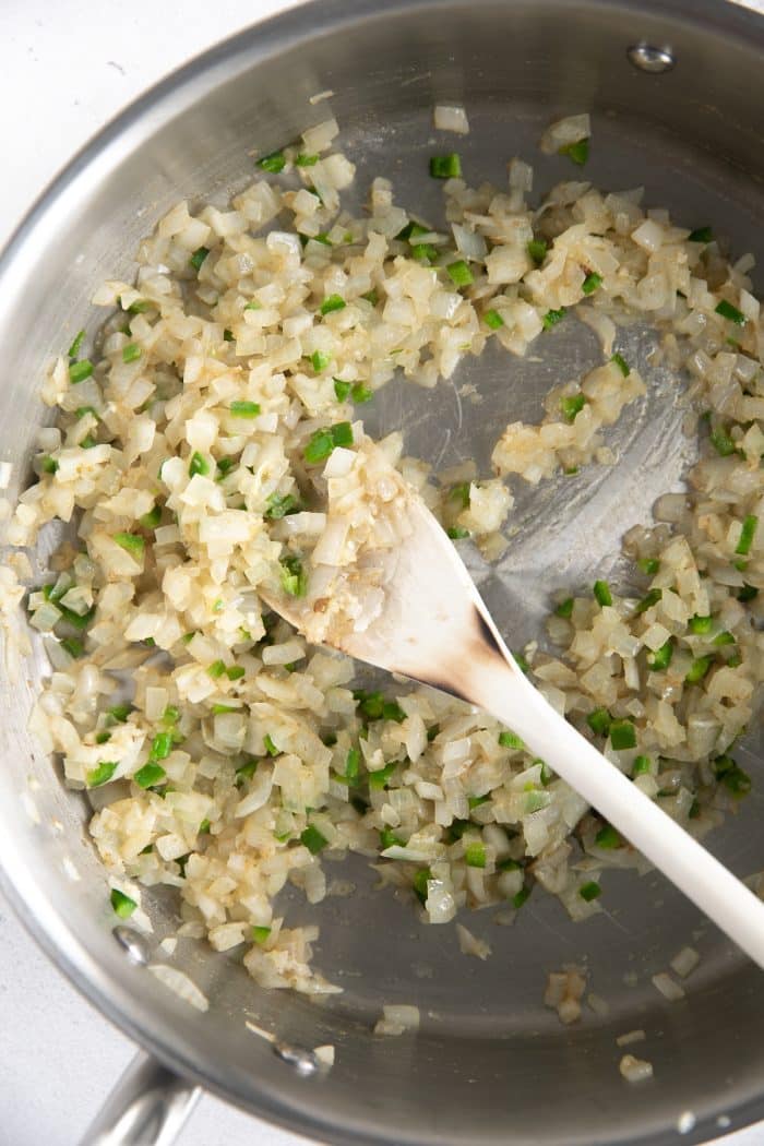 Onions, garlic, jalapeno, and cumin cooking in a medium pan over medium heat.