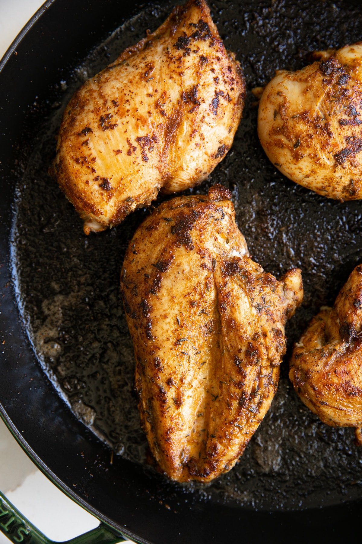 Searing blackened chicken breasts in a large skillet.