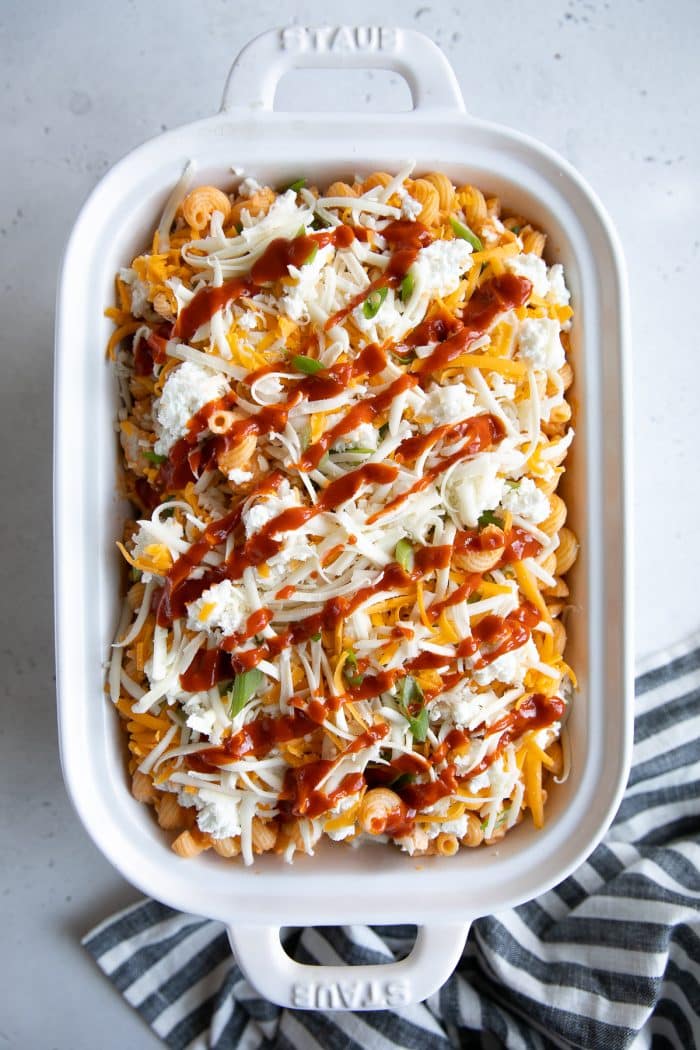 White baking dish filled with pasta noodles mixed with creamy buffalo sauce and chicken and topped with extra cheese.