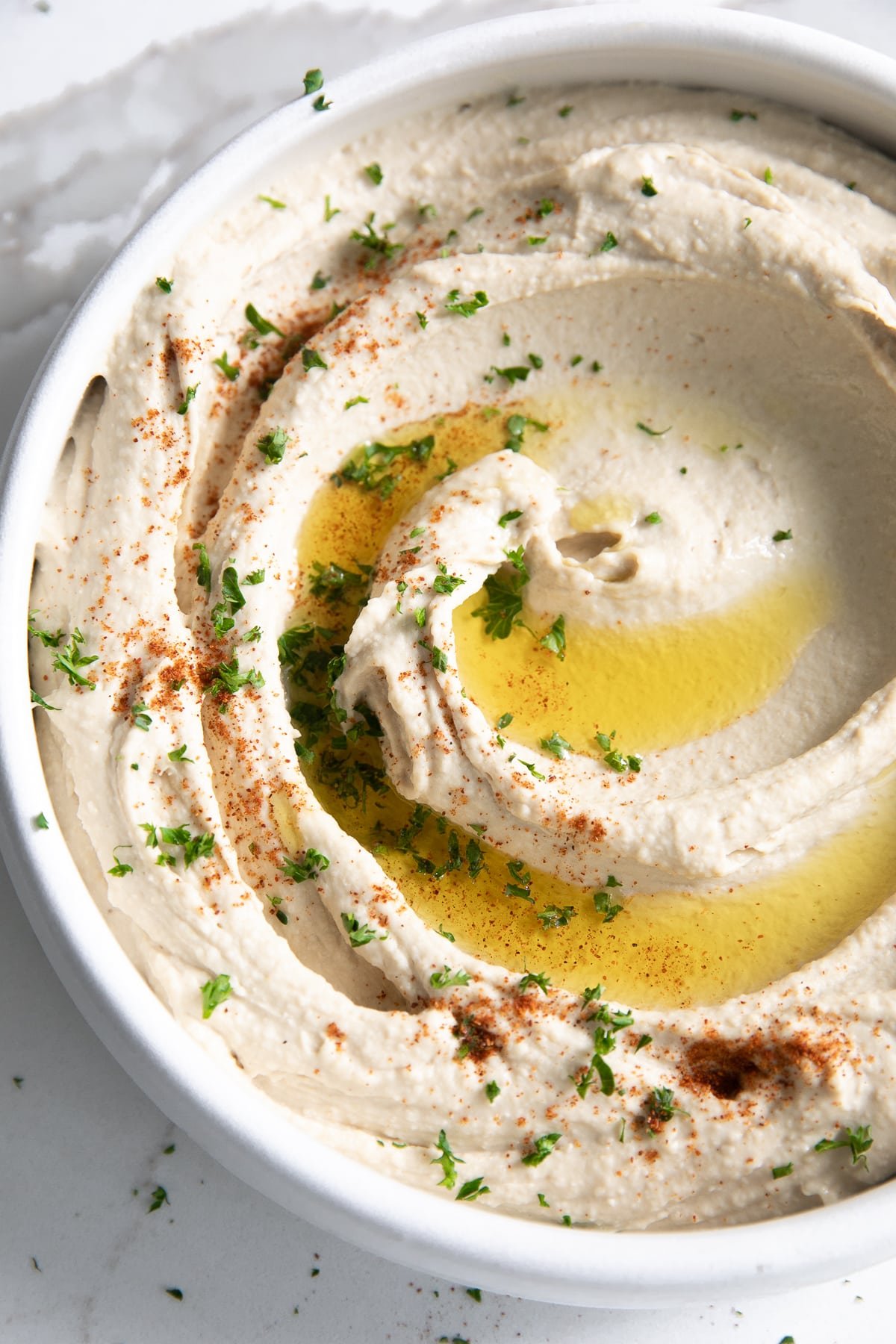 White bowl filled with creamy classic hummus.
