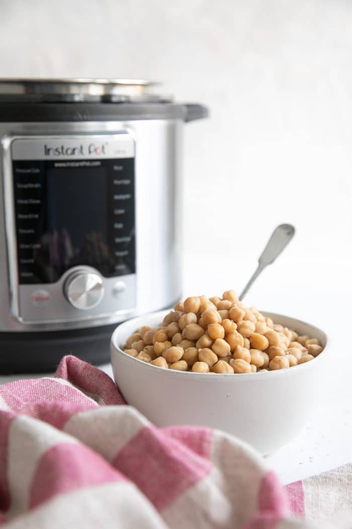 Bowl of cooked garbanzo beans with Instant Pot in the background.
