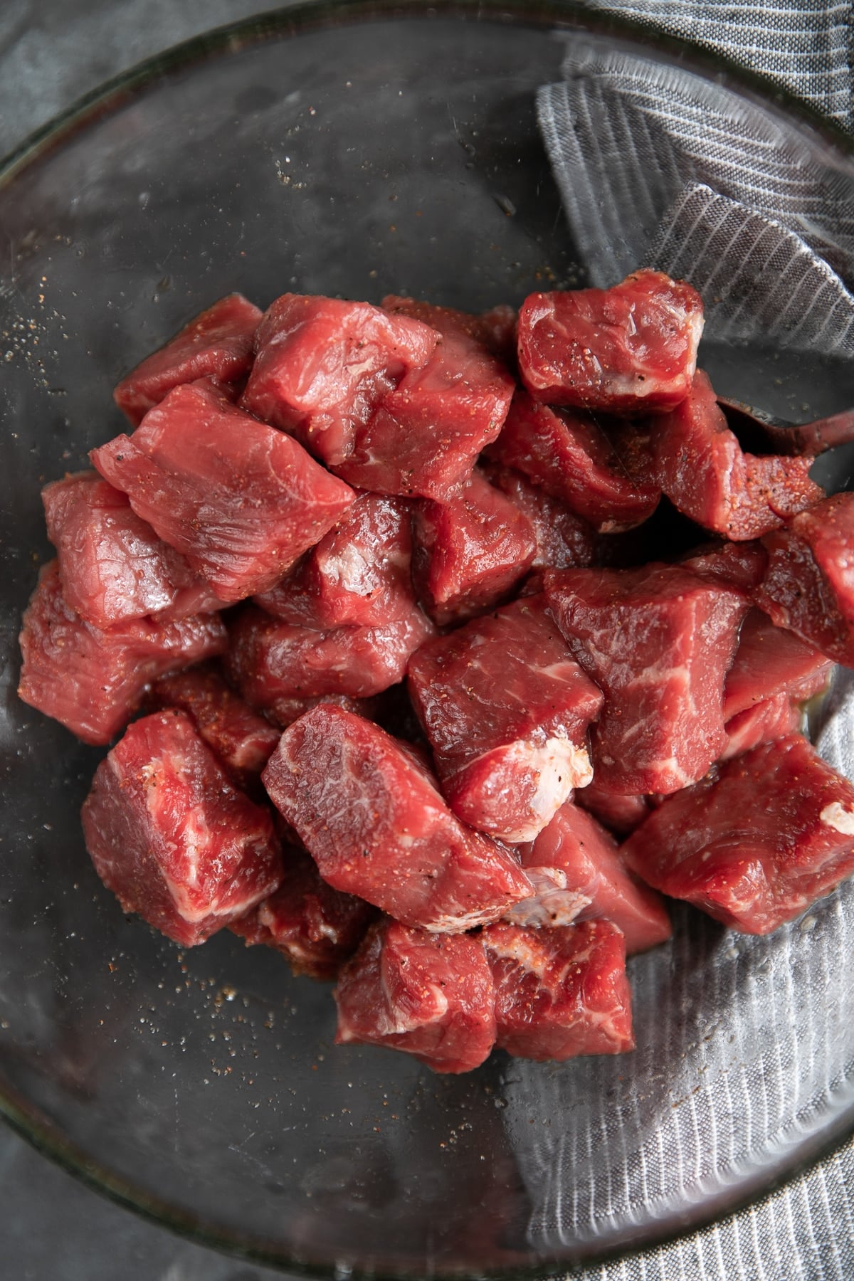 Cubes of steak in a medium glass mixing bowl.