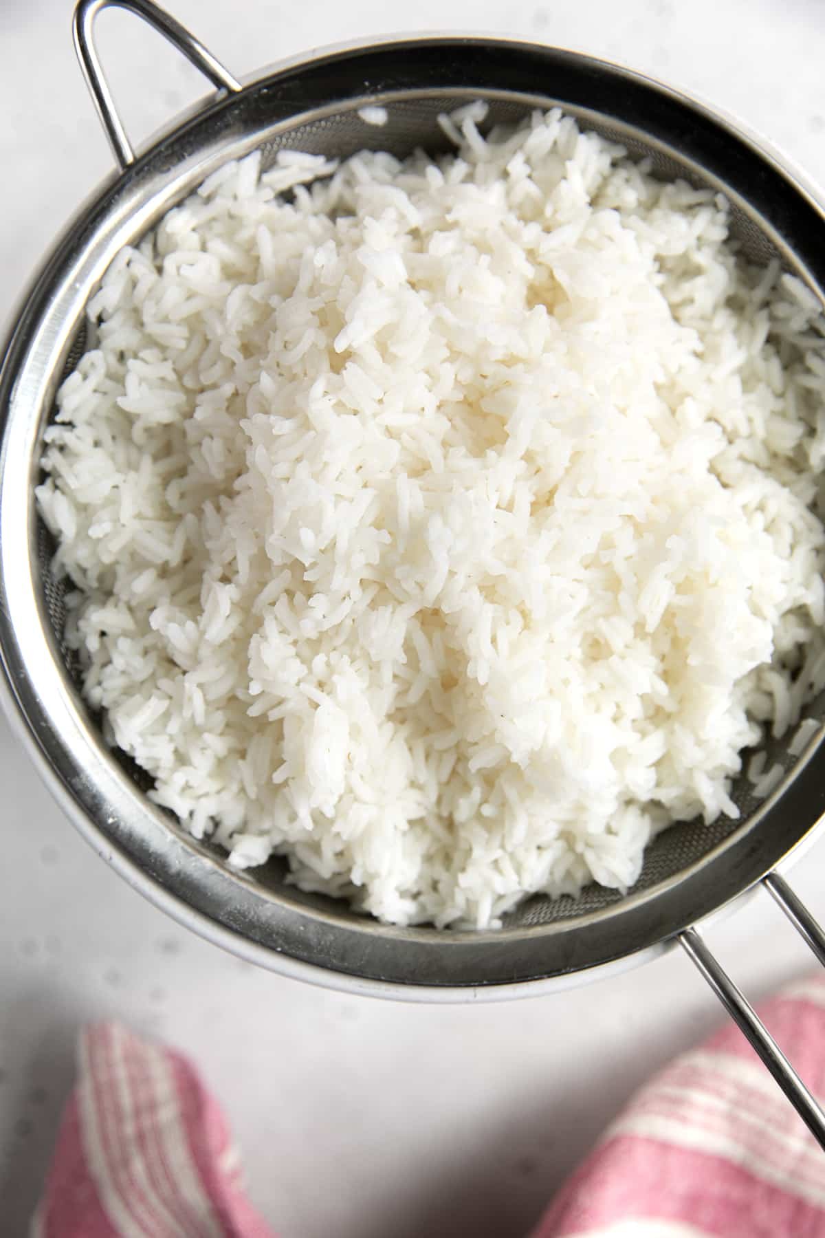 Draining cooked rice in a fine mesh strainer.