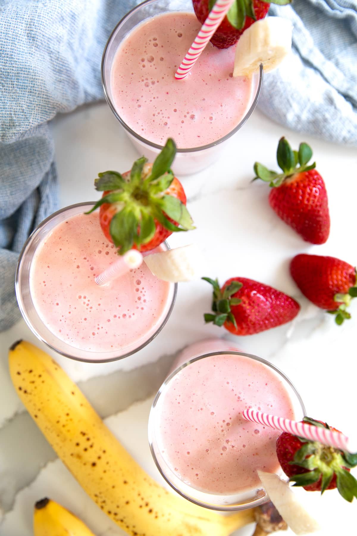Overhead image of three glasses filled with strawberry banana smoothie.