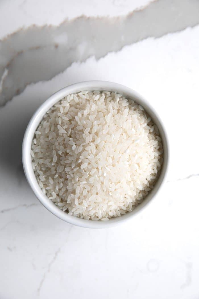 Uncooked white calrose rice in a small white dish.