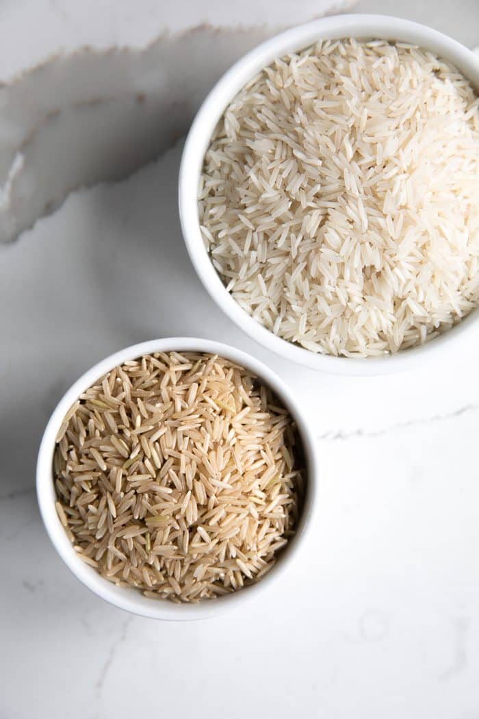 Two bowls filled with brown and white basmati rice.