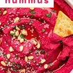 Bright pink beet hummus topped with sesame seeds and pine nuts, served with pita chips