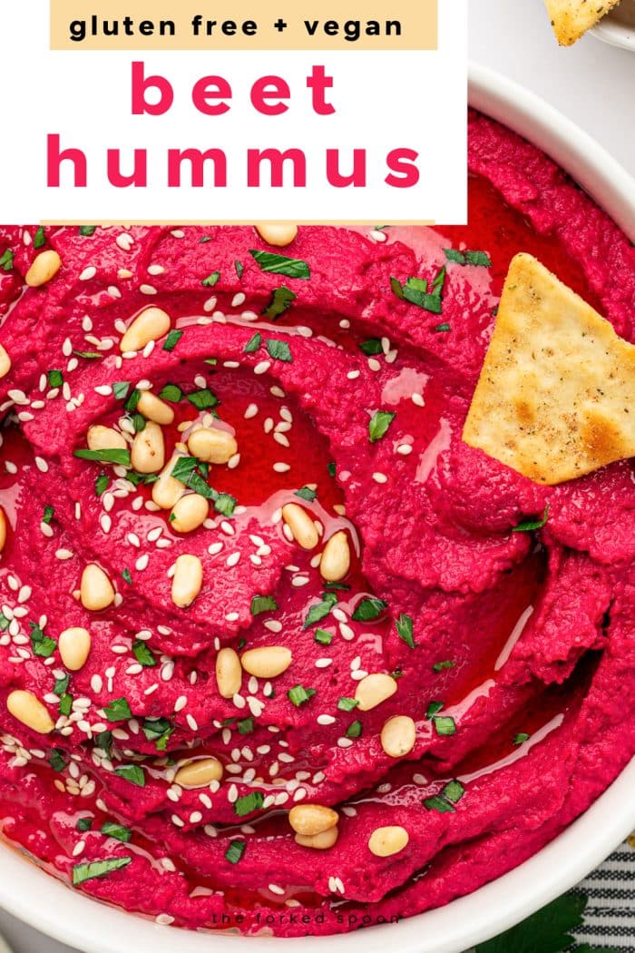 Bright pink beet hummus topped with sesame seeds and pine nuts, served with pita chips