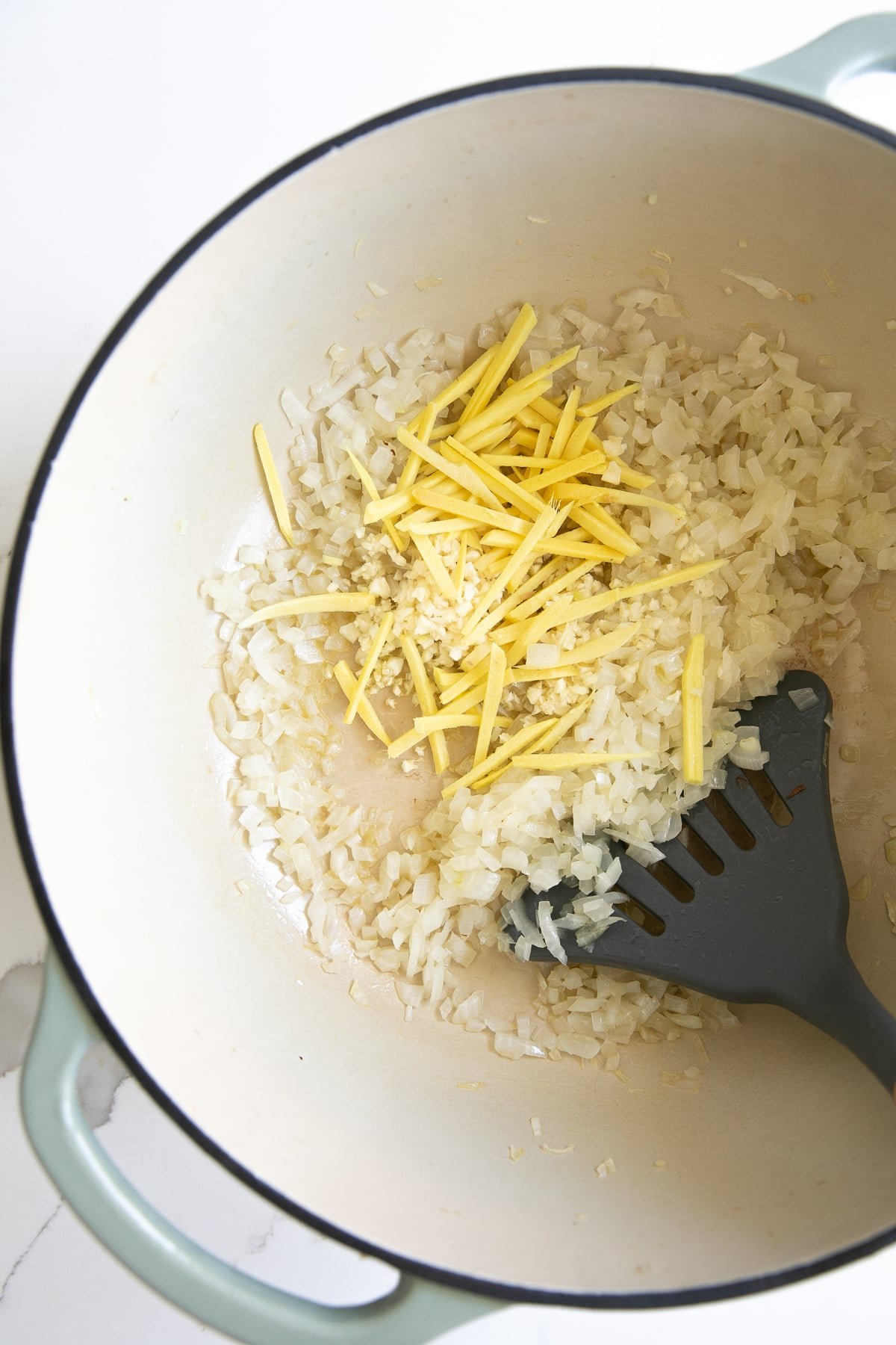 Toasting rice in a large pot with oil, garlic, and julienned ginger.