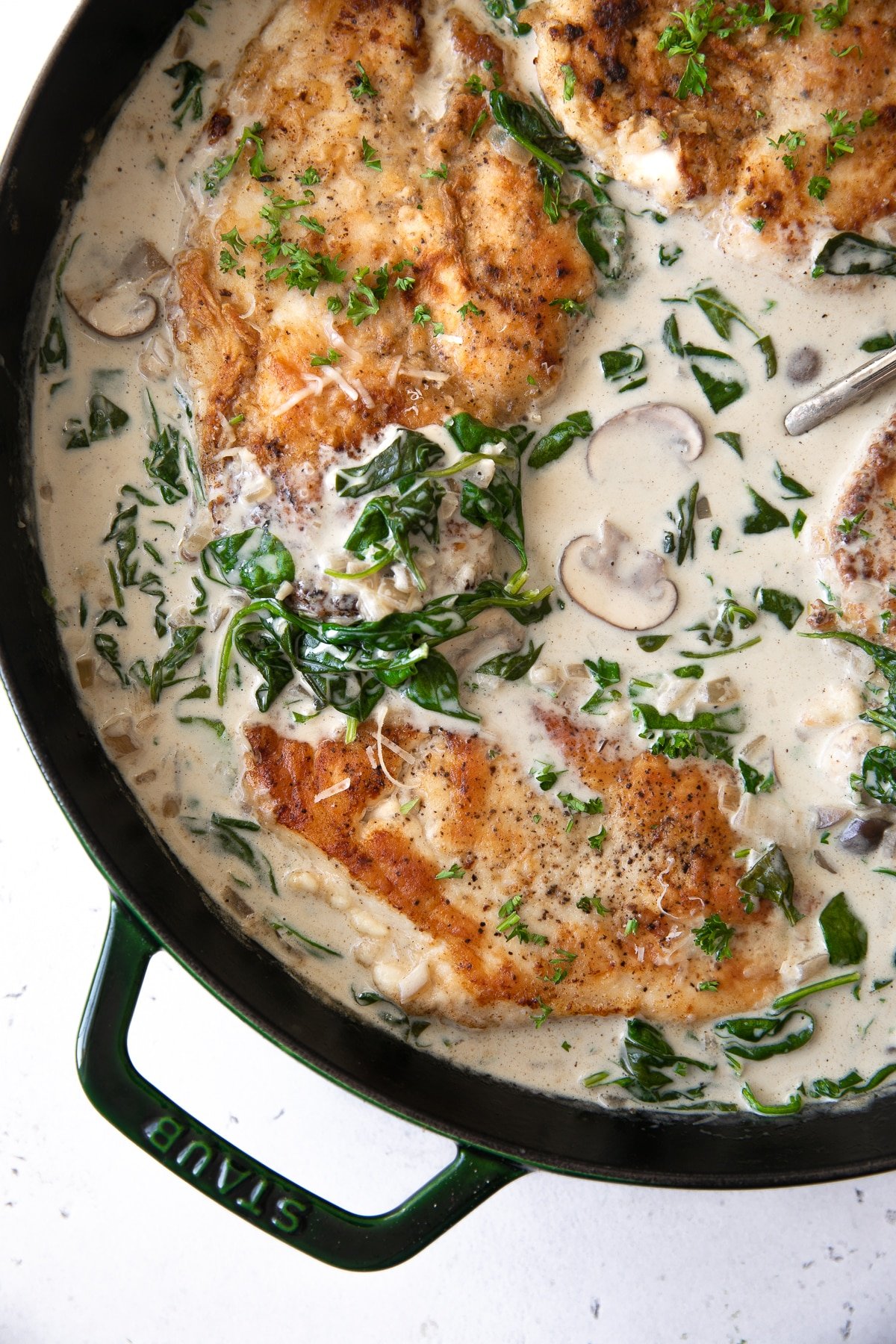 Skillet filled with a homemade cream sauce with mushrooms and spinach.