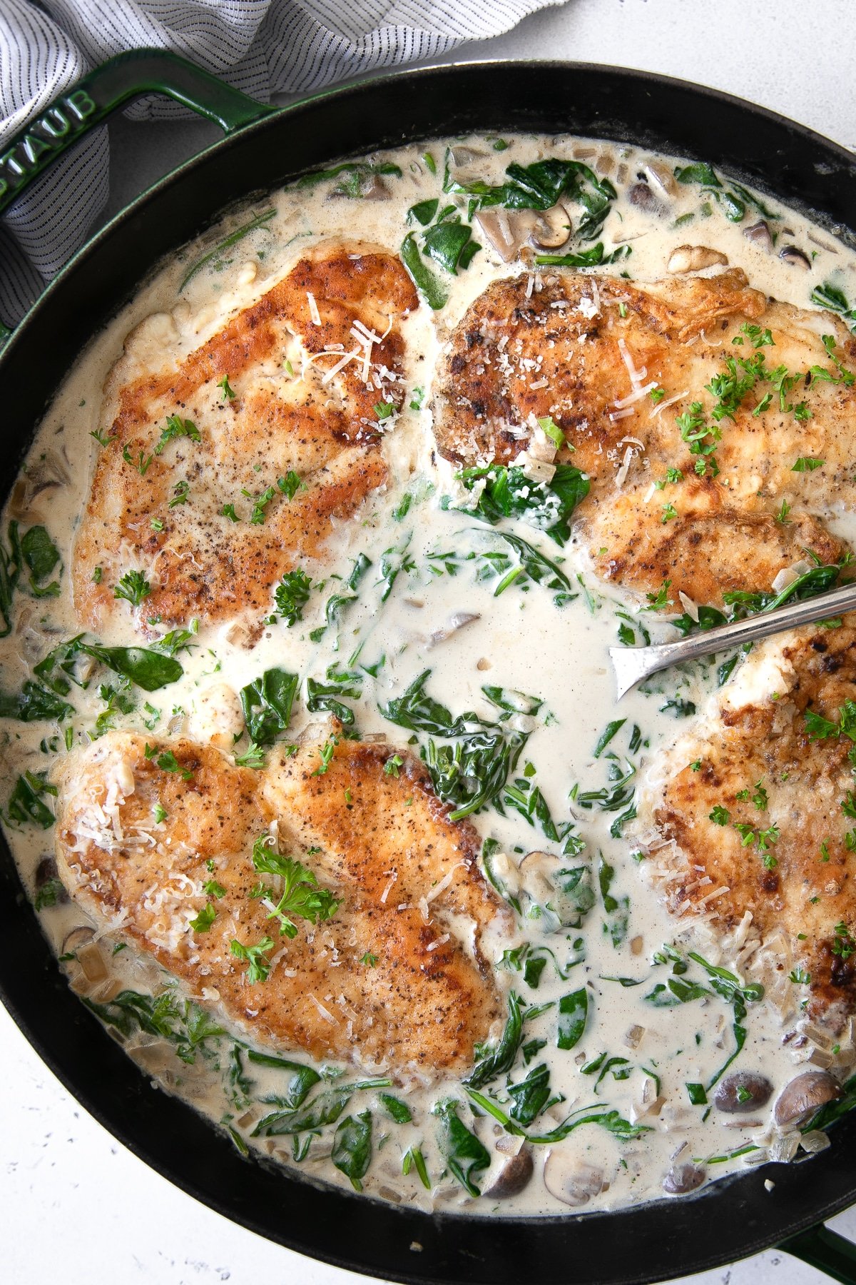 Large skillet filled with cooked chicken breasts in a creamy mushroom and spinach florentine sauce.