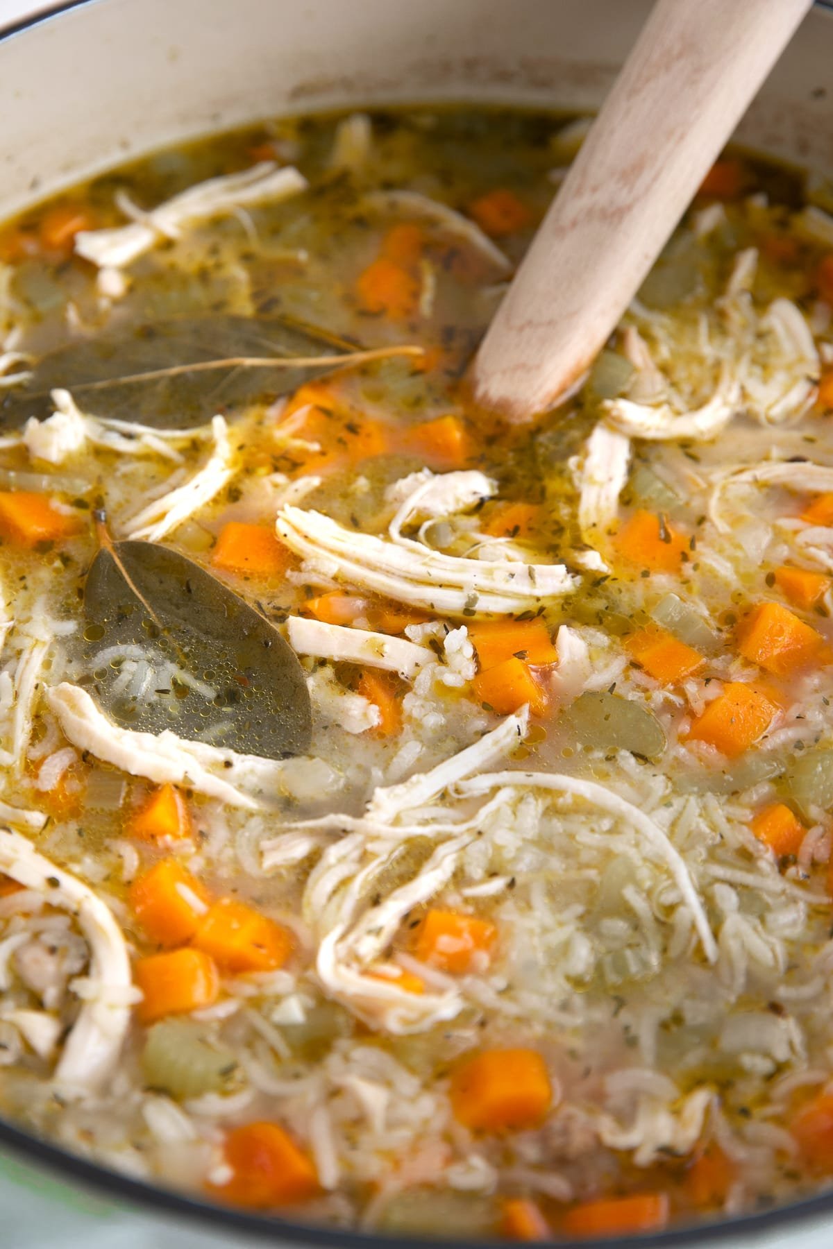 Large pot filled with chicken and rice soup loaded with carrots and celery.