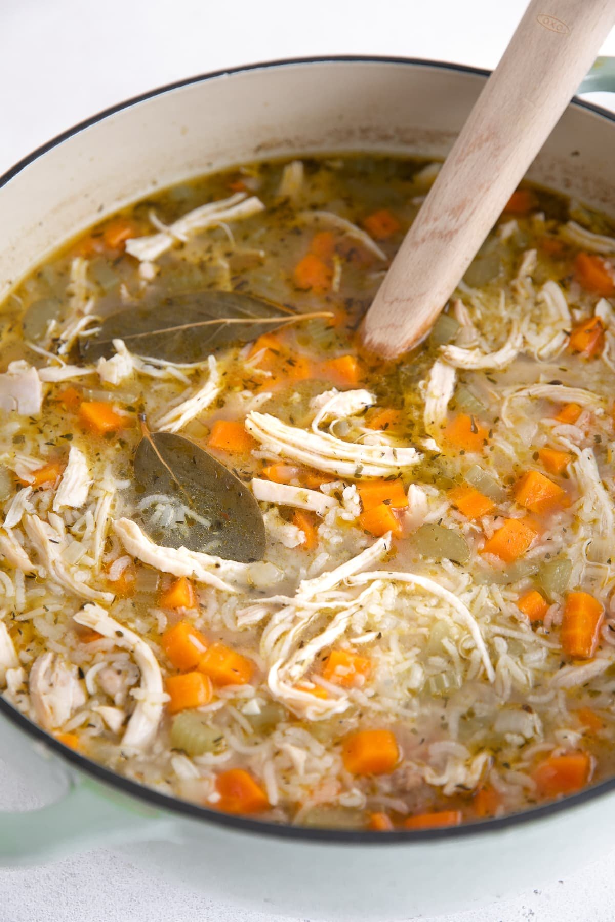 Large pot filled with chicken and rice soup loaded with carrots and celery.